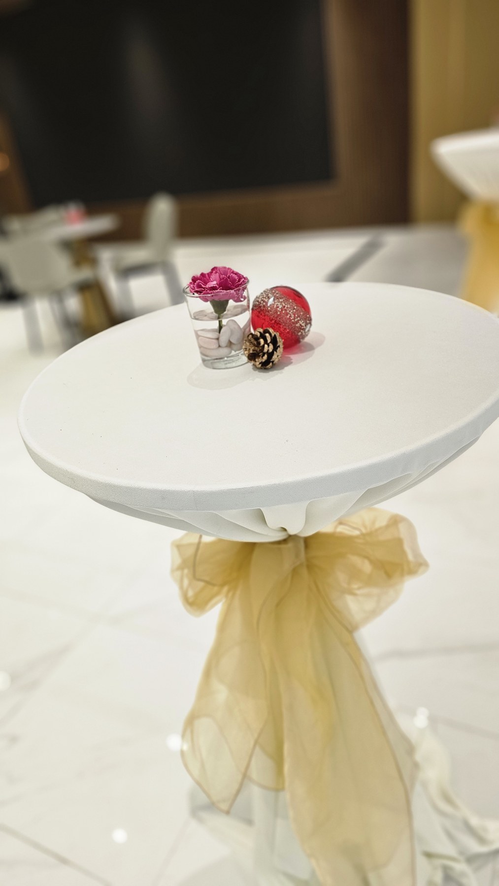 A cocktail table prepared with white linen and a floral centrepiece