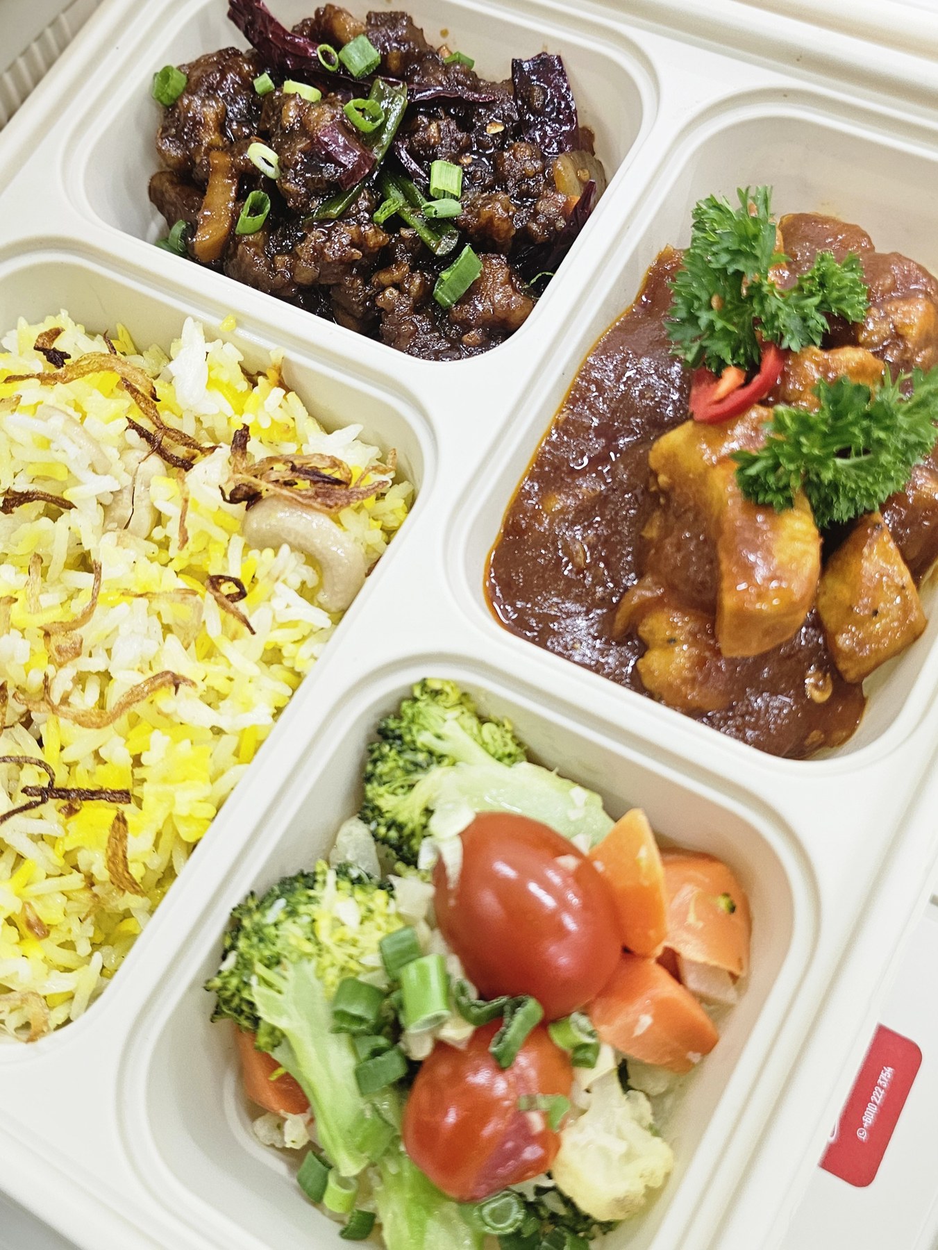Bento meal with yellow rice, curry and fresh vegetables